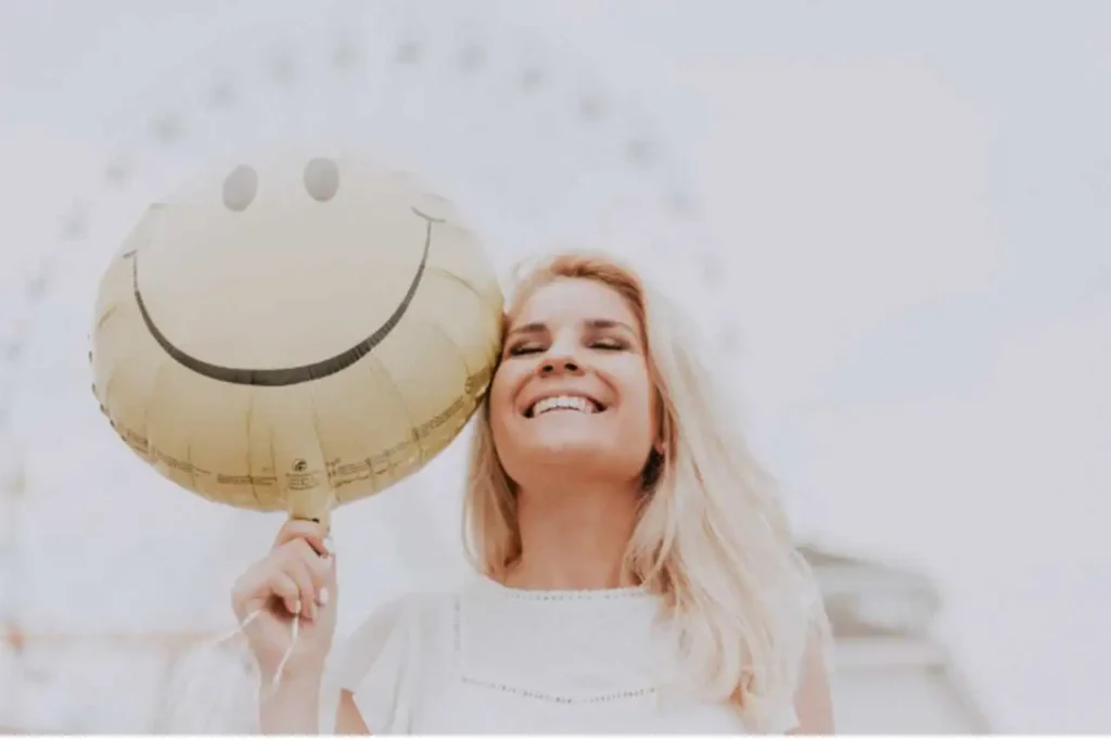 Mulher sorridente em parque de diversões, segurando balão com smile