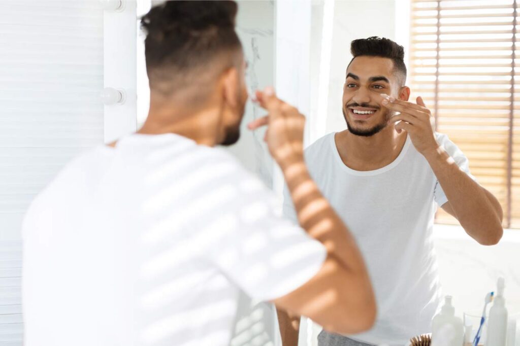 Homem vaidoso fazendo skincare em frente ao espelho